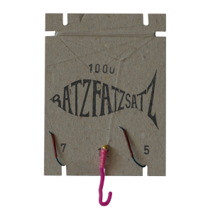 Der RatzFatzSatz 1000 (Pink) ist ein Angelhakenhalter aus Karton mit einer fischförmigen Grafik, zwei daran befestigten Angelhaken, einem rosa Köder und den Zahlen „7“ und „5“ an den unteren Ecken.