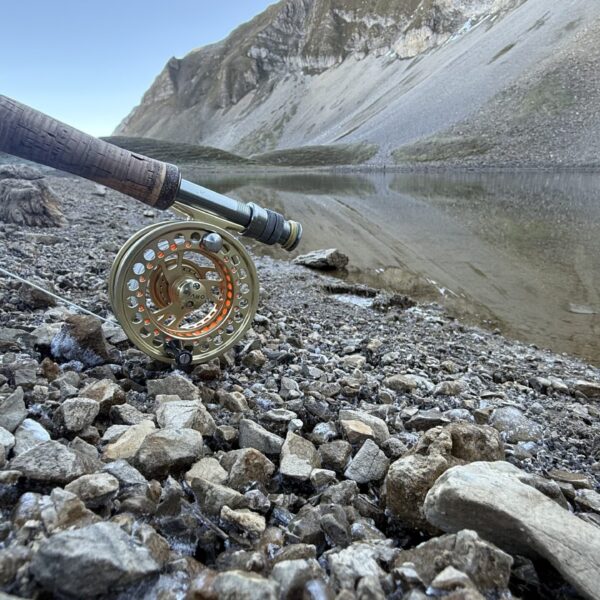 Fliegenfischer-Ausrüstung am Ufer eines Bergsees, inspiriert von 