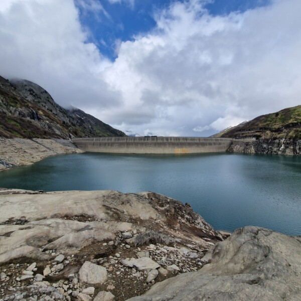 Lai da Nalps: Stausee mit Staumauer in malerischer Berglandschaft unter bewölktem Himmel.
