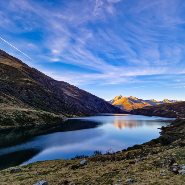 Lai da Nalps: Bergsee mit Spiegelung der Berge und blauem Himmel mit Wolken.