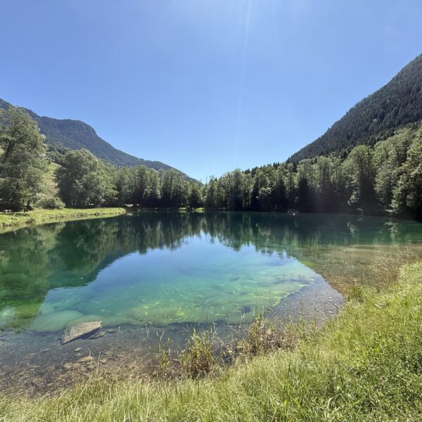 Kristallklarer Bergsee Laghetto Audan mit grünen Hügeln und blauen Himmel