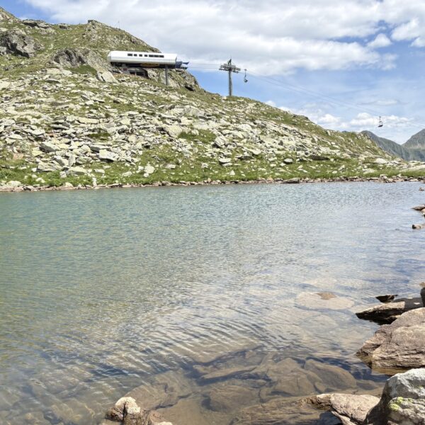 Bergsee mit Seilbahnstation und Felsen in den Alpen