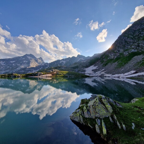 Lai Blau (Medel) Bergsee Spiegelung mit Wolken und Bergen im Hintergrund.