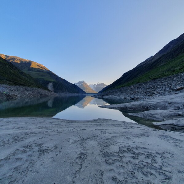 Lai da Curnera: Ruhiger Bergsee mit Spiegelung der Alpenlandschaft im klaren Wasser.