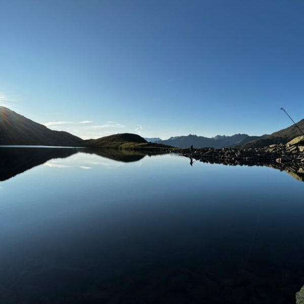 Sonnenaufgang am Lutersee (Andermatt) mit Angelruten und Bergpanorama.