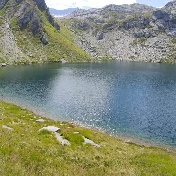 Portgerensee: blauer Bergsee mit grünen Wiesen und Felsen