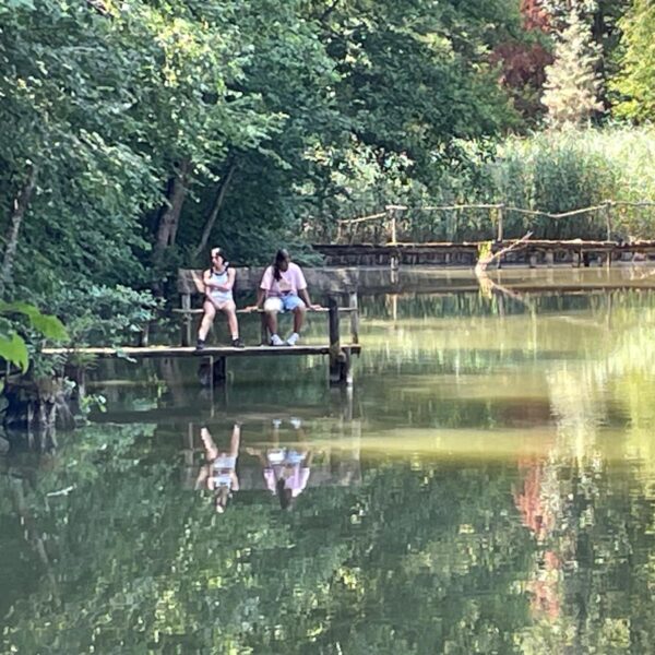 Zwei Personen sitzen auf einer Holzplattform am Scherzer Weiher.