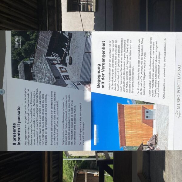 Ein zweisprachiges Informationsschild im Museo Poschiavino enthält italienischen und deutschen Text mit Fotos einer alten Mühle und eines modernen Gebäudes und beschreibt die Geschichte und Bedeutung des Museums.