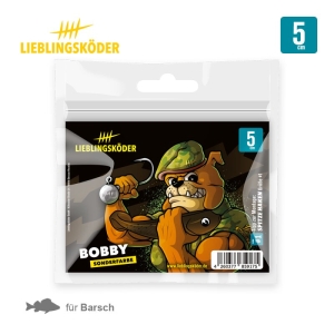 Eine Packung Bobby 5cm Angelköder für Barsche, mit einem muskulösen Cartoon-Hund in Tarnfarben, der seinen Arm mit einem Angelhaken schwingt. Auf dem Etikett steht "BOBBY SONDERFARBE.