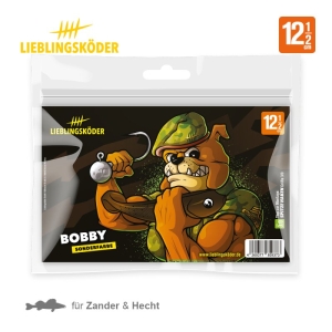 Eine Packung Lieblingsköder-Köder "Bobby 12,5cm" zeigt Bobby, einen muskulösen Cartoon-Hund in Armeeausrüstung mit einem großen Fisch. Die Verpackung zeigt "BOBBY SONDERFARBE" und das offizielle Lieblingsköder-Branding.