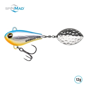 Der Jigmaster Flipper 12g ist ein SPINMAD-Angelköder mit einem blau-gelben Körper, Dreifachhaken und einem silbernen, blattförmigen Spinner.