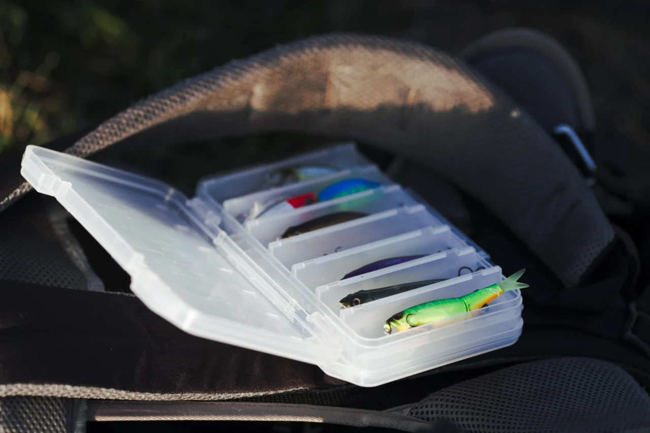 Angelköder in einer Tacklebox auf einem Rucksack. Gummiköder für Angler.