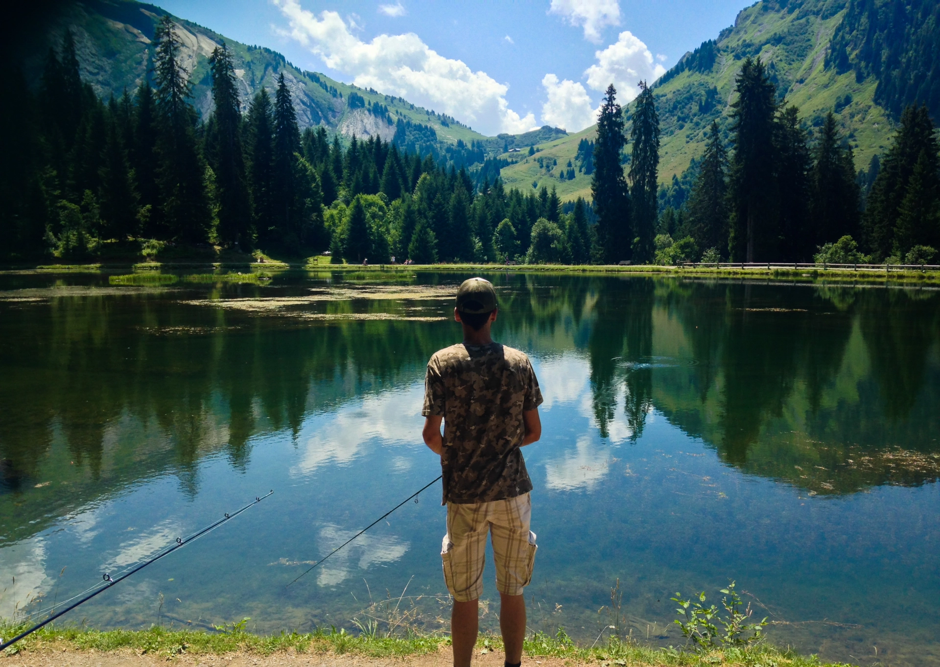 Angler am Schweizer Bergsee beim Fischen, umgeben von Alpenlandschaft. Paradies zum Angeln.