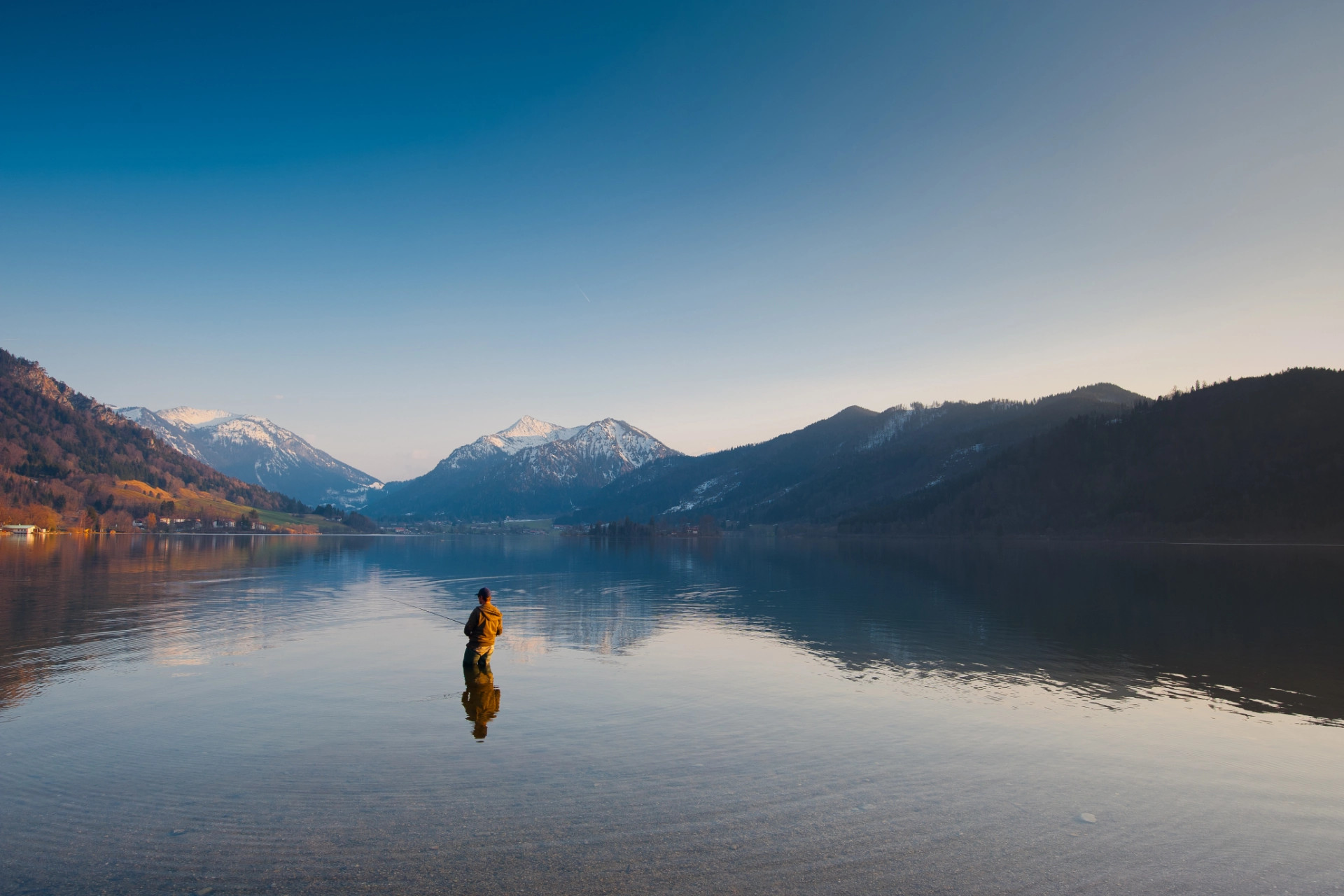 Angler im Bergsee vor Alpenkulisse beim Fischen und Angeln in Schweizer Bergseen.