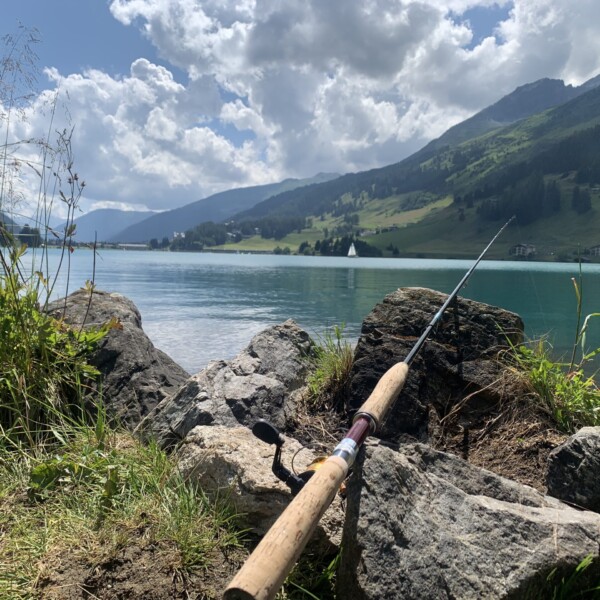 Angelrute am Davosersee vor Bergkulisse und blauem Wasser