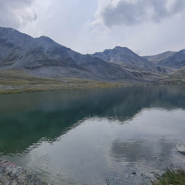 Illsee: Ruhiger Bergsee spiegelt Himmel und Berge wider.