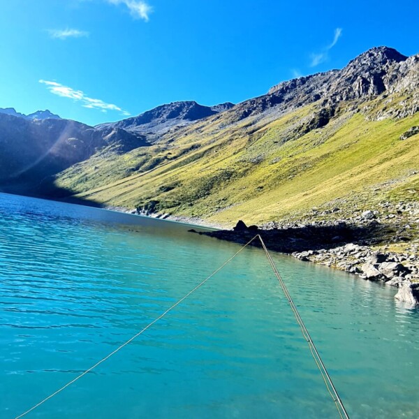 Lac de Cleuson: Türkisblauer Bergsee unter strahlend blauem Himmel mit grünen Hängen.