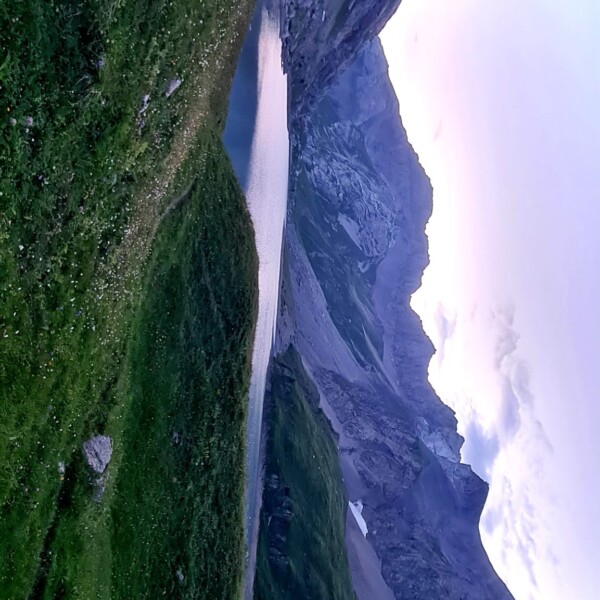 Sanetschsee: Bergsee umrahmt von grünen Hügeln und hohen Bergen im Abendlicht.