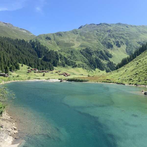 Schlappinsee: Türkisblauer Bergsee mit grünen Hängen und kleinen Häusern.