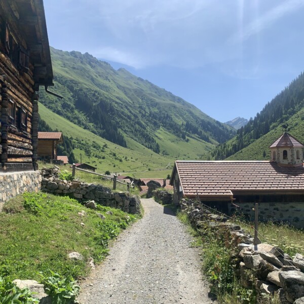 Idyllische Landschaft mit traditionellen Häusern in der Nähe des Schlappinsees, umgeben von grünen Bergen.