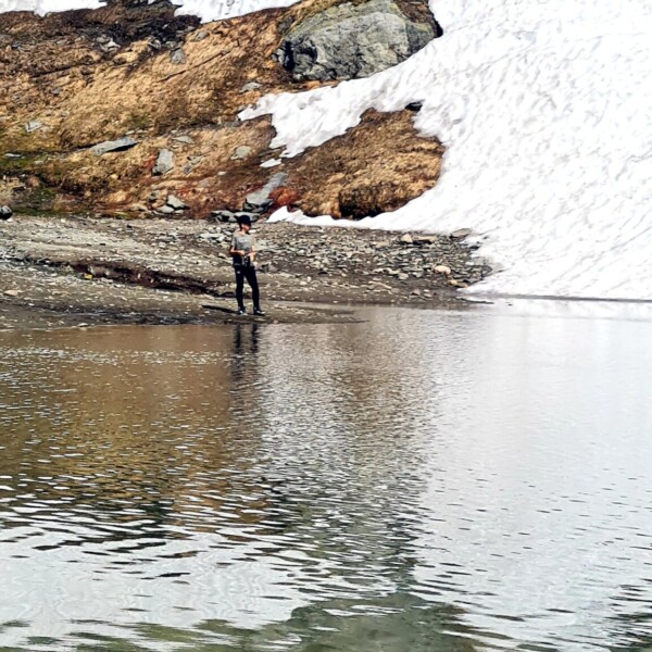Wanderer am Totensee mit Schnee und Felsen im Hintergrund