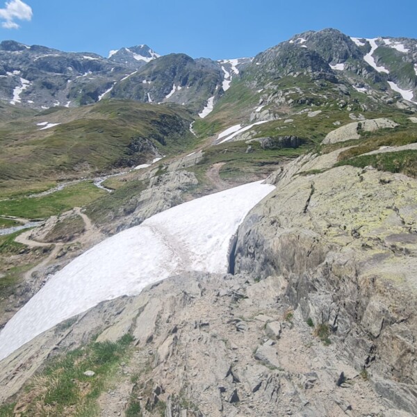 Berglandschaft am Totensee mit Schnee und Wanderweg.