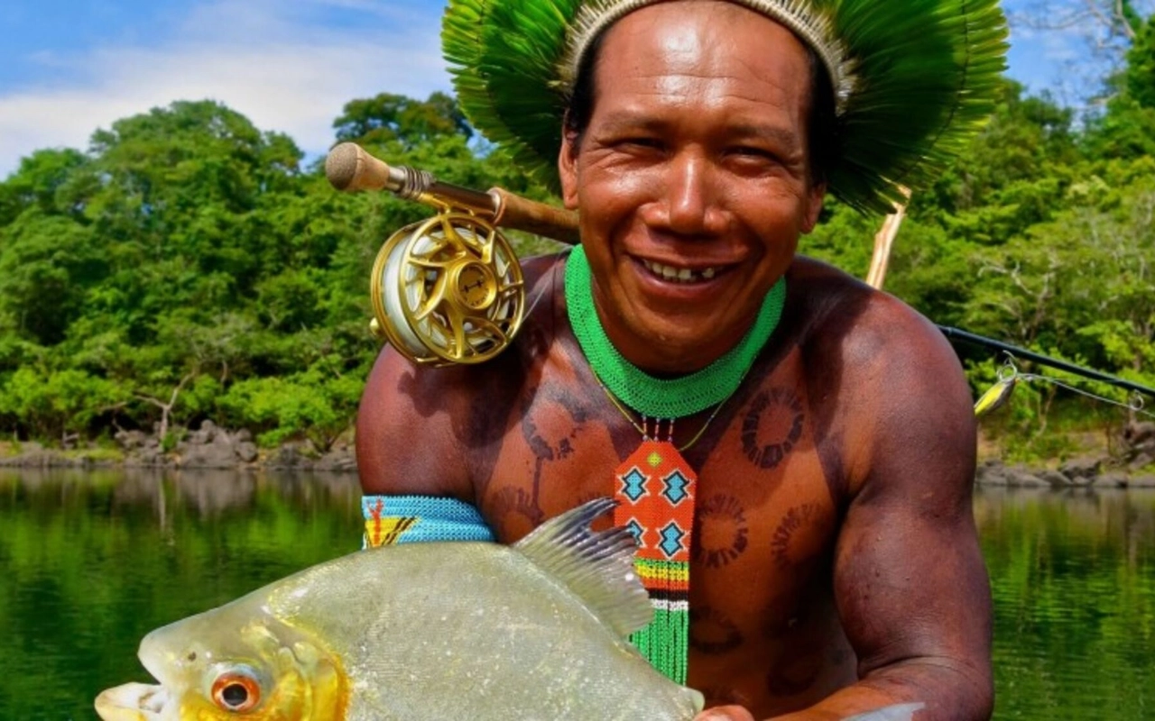 Indigener Mann mit Fisch, Angelrute und Kopfschmuck. Amazonas-Reise.