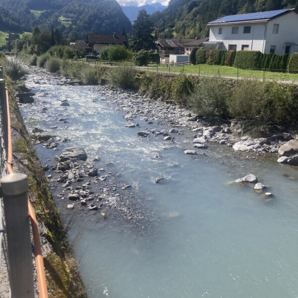 Taschinasbach Fluss mit blauem Wasser in einer grünen Landschaft.