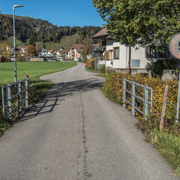 Straße in Alpbach (Escholzmatt) mit Geschwindigkeitsbegrenzung 50. Hügelige Landschaft im Hintergrund.