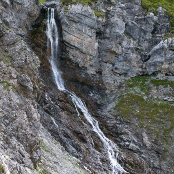 Alteinbach Wasserfall stürzt über eine felsige Bergwand herab. Grün bewachsene Felsen.