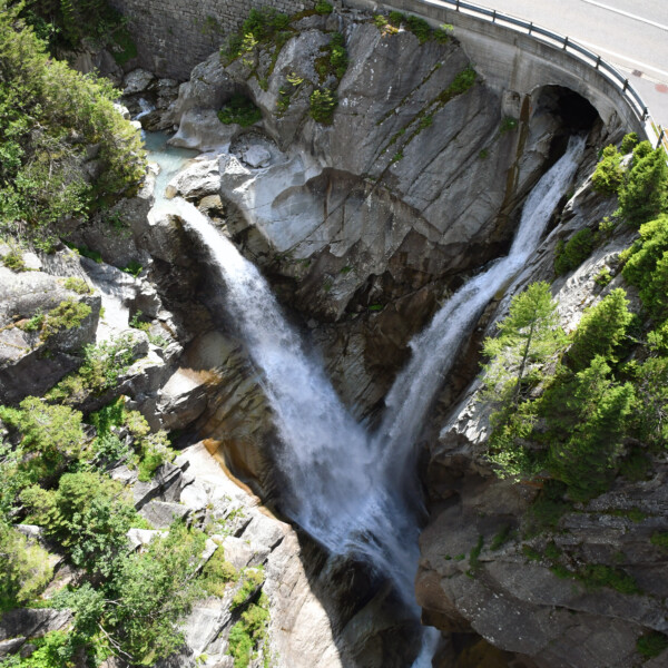 Doppelter Wasserfall unter der Ärlenbach-Brücke, umgeben von Felsen und Grün. Spektakuläre Natur.