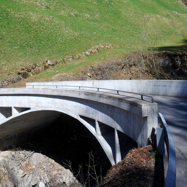 Betonbrücke über den Bolbach mit grüner Wiese im Hintergrund.