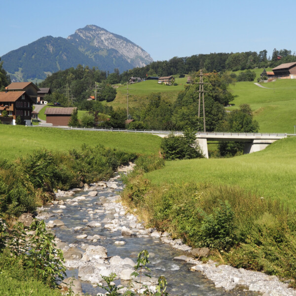 Choltalbach in Emmetten, Schweiz mit Brücke, grünen Wiesen und Bergkulisse.