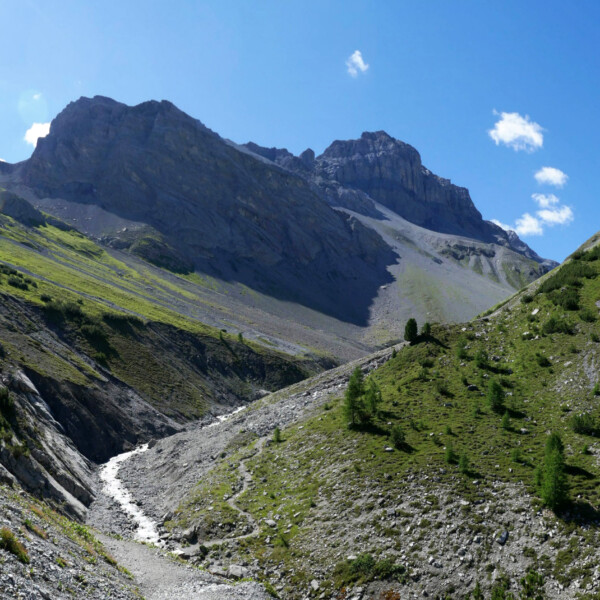 Ducanbach Gebirgsbach mit Bergpanorama und blauem Himmel. Wanderweg in Graubünden.