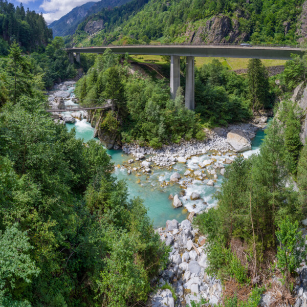 Fluss Fellibach unter einer hohen Brücke in einer grünen Landschaft.