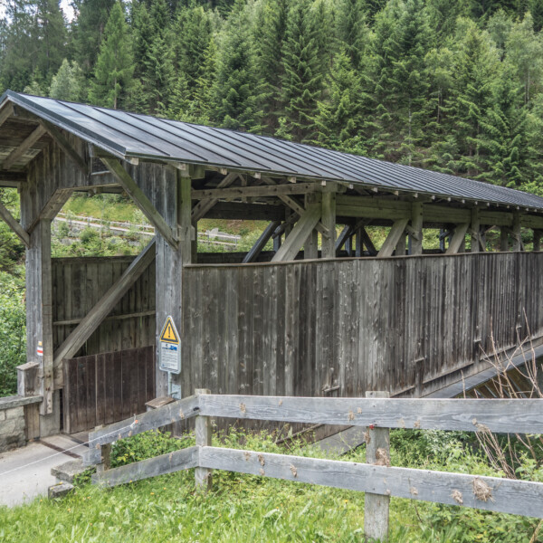 Gedeckte Holzbrücke vor grünem Wald. Fundogn Brücke.