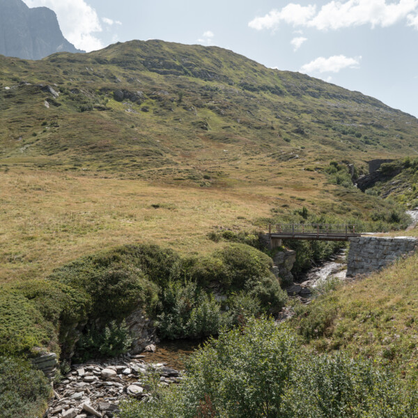 Maseggbach: Brücke über einen Bach in einer grünen Berglandschaft.