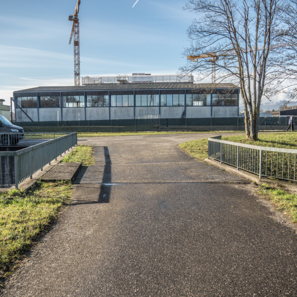 Mooskanal: Weg über Brücke mit Gebäude, Kran und Van im Hintergrund.