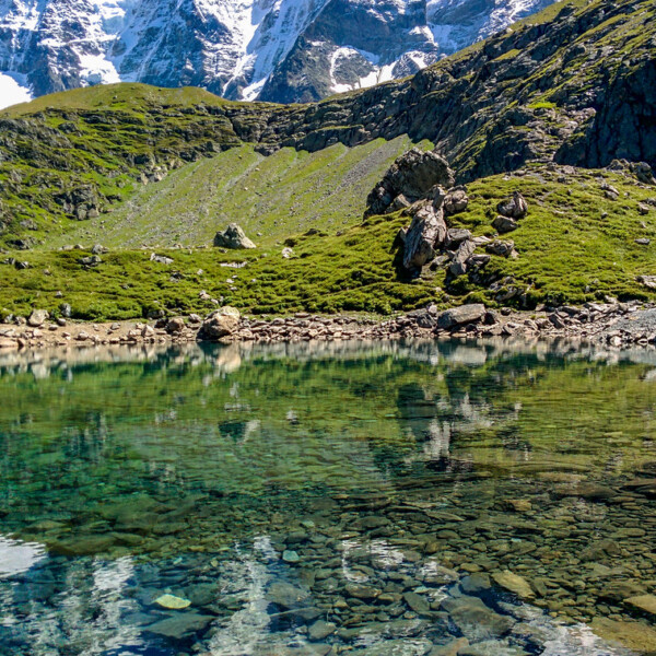 Oberhornsee: Klarer Bergsee mit schneebedeckten Gipfeln und grüner Uferlandschaft.