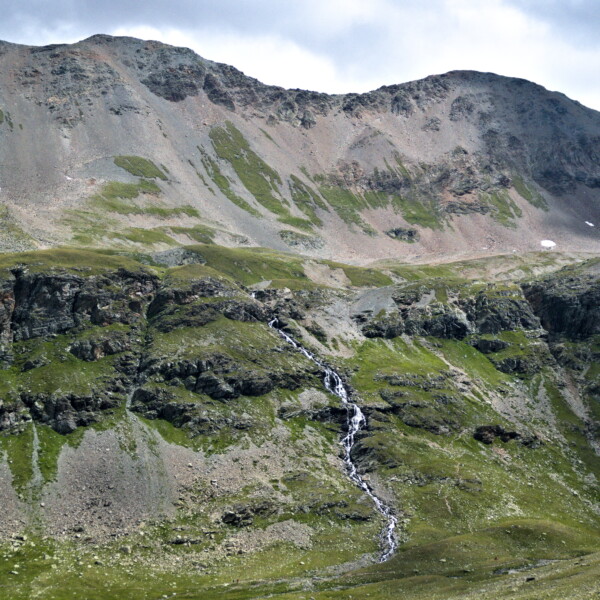 Wasserfall am Ovel da Languard Berg. Schroffe Felsen und grüne Vegetation.