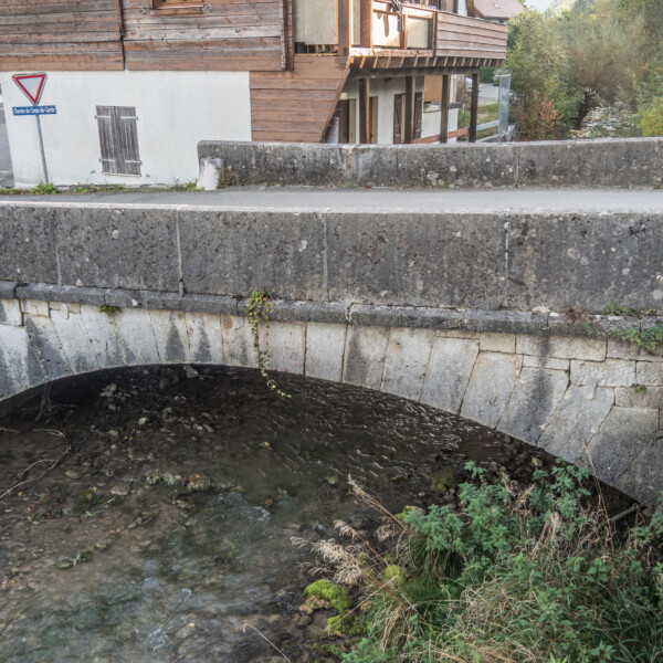 Steinbrücke über Bachlauf. Schild 