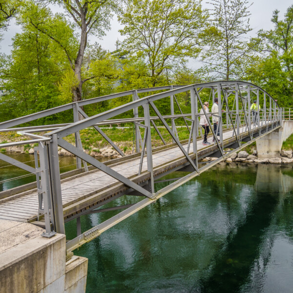 Fußgängerbrücke über die Reppisch mit Personen im Grünen.