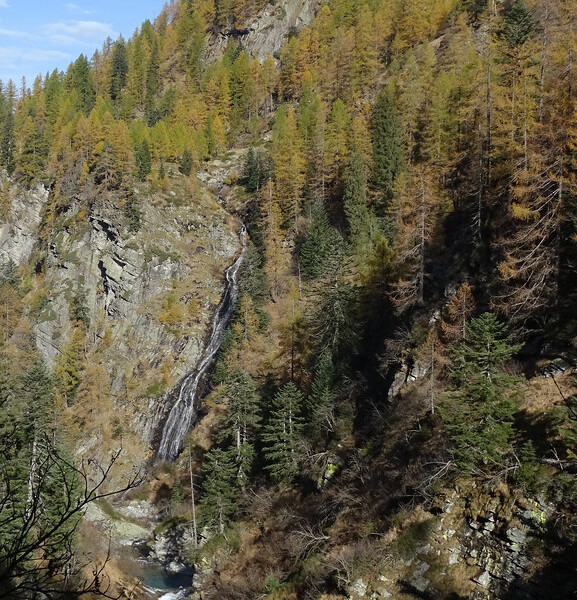 Wasserfall im Herbstwald bei Ri del Lago. Gelbe und grüne Bäume am Berghang.