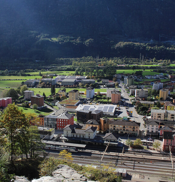 Blick auf Biasca und Ri della Froda Wasserfall mit Bergkulisse.