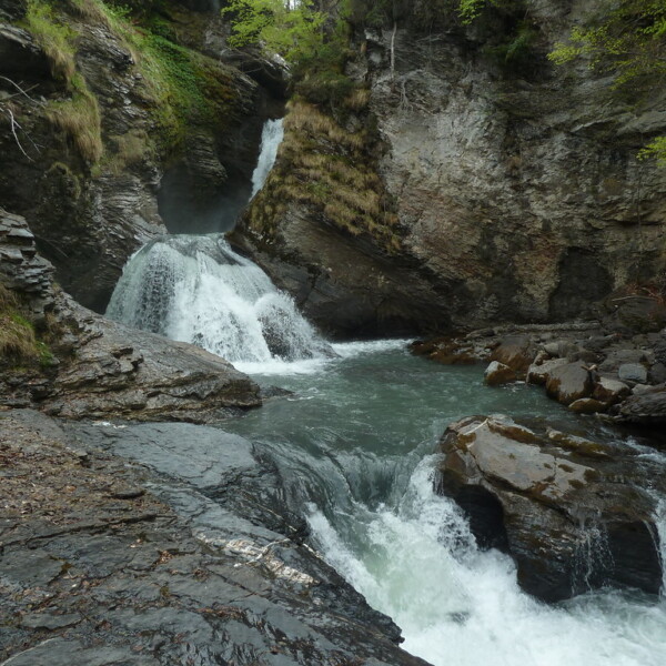Rychenbachfall: Mehrstufiger Wasserfall mit Felsen und üppigem Grün.
