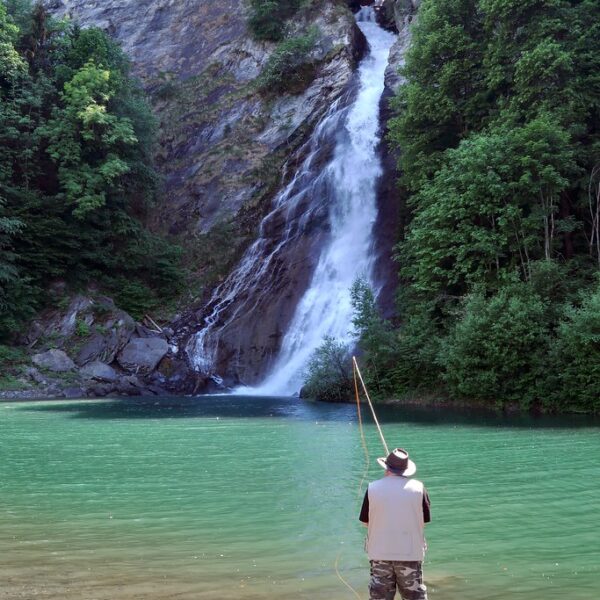 Angler am Saar-See vor Wasserfall, malerische Naturkulisse.