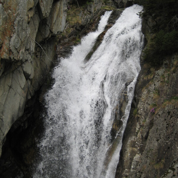 Wasserfall Salanfe zwischen Felsen mit einer kleinen Brücke oben.