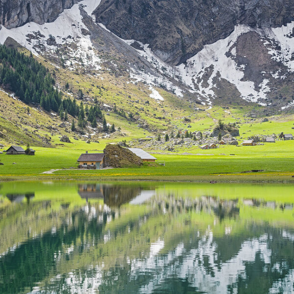 Seealpsee Spiegelung mit Alpenhäusern und Bergen im Hintergrund.