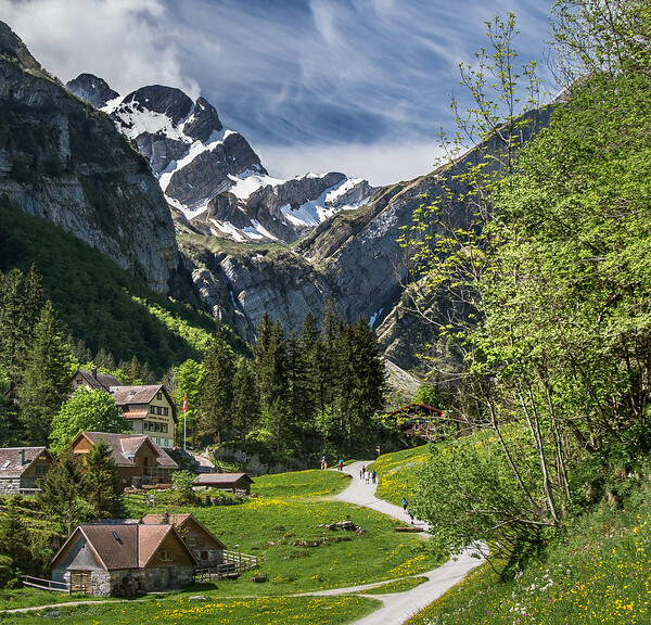 Seealpsee: Idyllische Landschaft mit Häusern, Wiesen und schneebedeckten Bergen in den Schweizer Alpen.