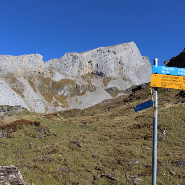 Wanderwegweiser in Seelenen, Schweiz, mit Blick auf felsige Berge. 